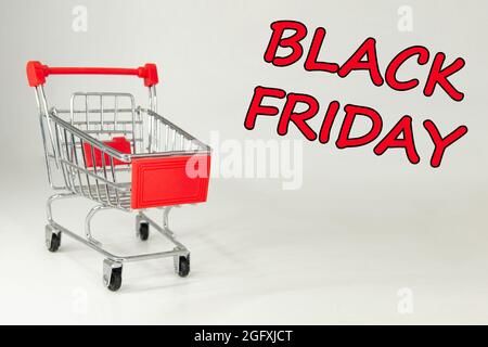 Schwarzer Freitag, 2021. Design für Black Friday, begleitet von einem Metalleinkaufwagen für die riesigen Verkäufe an diesen Terminen. Weißer Hintergrund. Platz für Text. Stockfoto