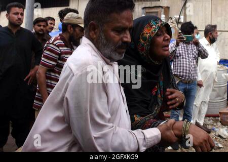 Karachi, Pakistan. August 2021. Eine Frau trauert am 27. August 2021 über den Tod ihrer Verwandten am Standort eines Fabrikfeuers in Karachi, Provinz Sindh, Südpakistan. Ein Brand in einer Chemiefabrik in Pakistans südlicher Hafenstadt Karachi tötete am Freitag mindestens 15 Arbeiter, teilte Polizei und Rettungsbeamte mit. Quelle: Str/Xinhua/Alamy Live News Stockfoto