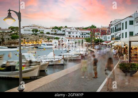 Menorca, Spanien - 20. august 2021: Menschen im Hafen es Castell, bei Sonnenuntergang touristische Stadt mit weißer Architektur und Gebäuden in Menorca, Spanien Dur Stockfoto