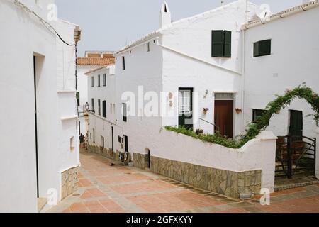 Blick auf die Gassen und Straßen weiße Architektur und Gebäude der Stadt Es Mercadal, Menorca, Spanien während der Sommersaison. Leere Straße mit Nobo Stockfoto