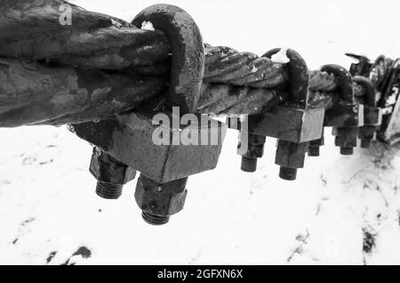 Schwarzes Stahlseil mit Endbefestigungsschlössern, Schwarz-Weiß-Foto mit selektivem Fokus Stockfoto