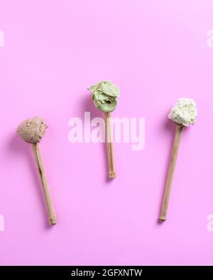 Draufsicht auf drei Holzlöffel auf einem leuchtend rosa Hintergrund mit Eisschaufeln auf ihnen Stockfoto