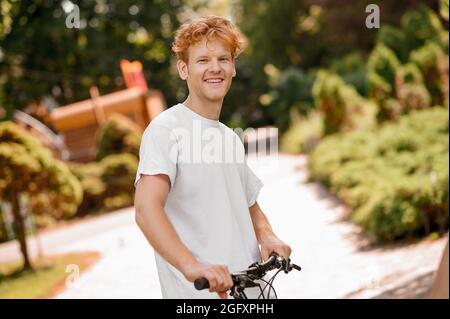 Hochmütig athletischer kaukasischer Kerl mit seinem Fahrrad Stockfoto