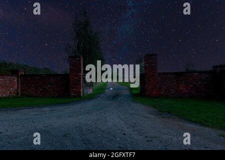 Tor und Zufahrtsstraße zur Residenz in der Nacht, in Dunkelheit gehüllt. Stockfoto