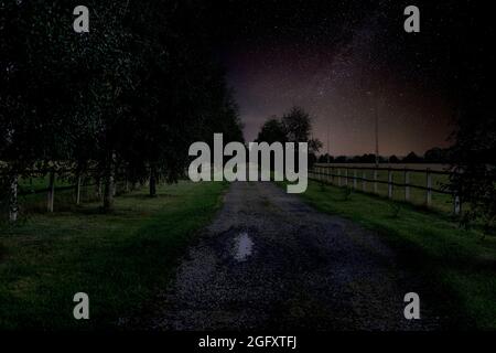 Tor und Zufahrtsstraße zur Residenz in der Nacht, in Dunkelheit gehüllt. Stockfoto