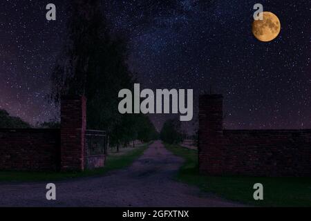 Tor und Zufahrtsstraße zur Residenz in der Nacht, in Dunkelheit gehüllt. Am Himmel sieht man den Mond zur Seite. Stockfoto