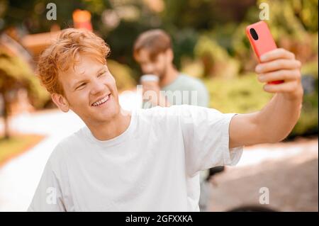 Fröhlicher hübscher Kerl, der ein Selfie im Freien nimmt Stockfoto