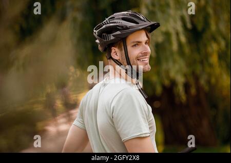 Fröhlicher Sportler in schützender Kopfbedeckung, der wegschaut Stockfoto