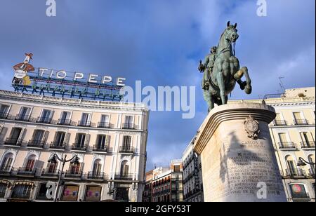 Das berühmte Tio Pepe Reklameschild erhebt sich über eine Statue von König Carlos III, an der Puerta del Sol, Madrid, Spanien. Stockfoto