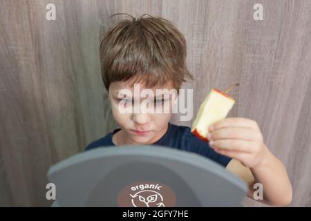 Kind Junge werfen Apfelkern zu Abfalleimer für Bio zu Hause. Aufklärung über das Konzept der Abfalltrennung Stockfoto