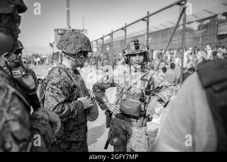 US Marine Brig. General Farrell J. Sullivan, der Kommandeur der Marine Amphibious Task Force 51/5th Marine Expeditionary Brigade, spricht während einer Evakuierung am Hamid Karzai International Airport, Kabul, Afghanistan, am 24. August mit einem Dienstmitglied der italienischen Koalitionstruppe. US-Dienstmitglieder und Koalitionsstreitkräfte unterstützen das Außenministerium bei einer nicht-kämpferischen Evakuierungsoperation (NEO) in Afghanistan. (USA Marine Corps Foto von Staff Sgt. Victor Mancilla) Stockfoto