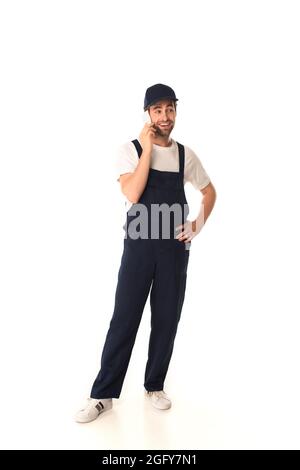 Lächelnder Mitarbeiter des Reinigungsdienstes, der auf weißem Hintergrund mit dem Mobiltelefon spricht Stockfoto