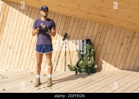 Region Perm, Russland - 13. August 2021: Wanderer nahm seinen Rucksack ab und ruht auf einer hölzernen Aussichtsplattform in einem Pavillon auf der ausgestatteten Touristenroute Stockfoto