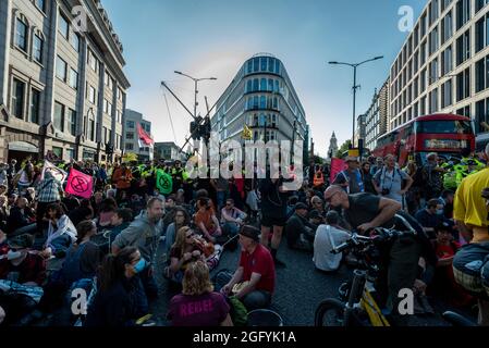 London, Großbritannien. 27. August 2021. Klimaaktivisten von Extinction Rebellion inszenieren einen Protest, der den Verkehr vor der U-Bahnstation Mansion House in der Queen Victoria Street in der City of London blockiert. Die Veranstaltung ist Teil des Protestes ‘Unmögliche Rebellion’, um „die Ursache der Klima- und Umweltkrise anzuvisieren“ und dauert zwei Wochen, bis die Regierung zustimmt, alle Investitionen in neue fossile Brennstoffe zu stoppen. Kredit: Stephen Chung / Alamy Live Nachrichten Stockfoto