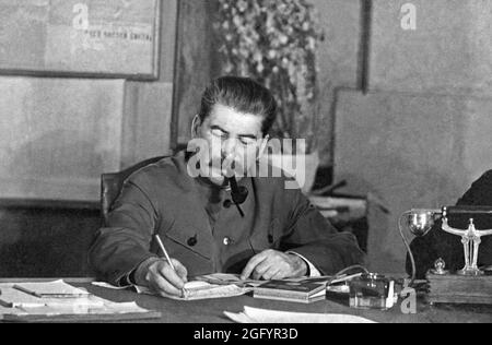 Joseph Stalin schrieb mit seiner Pfeife an einem Schreibtisch auf einer Konferenz im Kreml, Moskau, März 1935. Er schreibt mit seinem charakteristischen farbigen Bleistift, mit dem er alles schrieb. Stockfoto