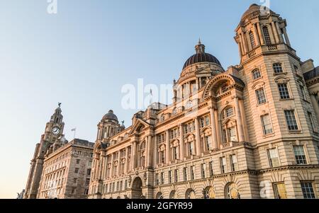 Multi-Image-Panorama der drei Grazien am Liverpooler Ufer, das bei Sonnenuntergang im August 2021 in goldenes Licht getaucht wurde. Stockfoto