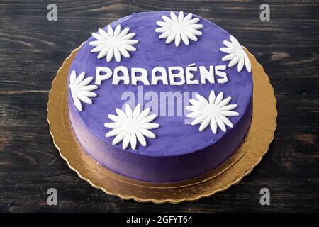 Ein schöner Concept Cake aus blau-violetter Buttercreme und Blumen. Auf einem Holztisch. Stockfoto