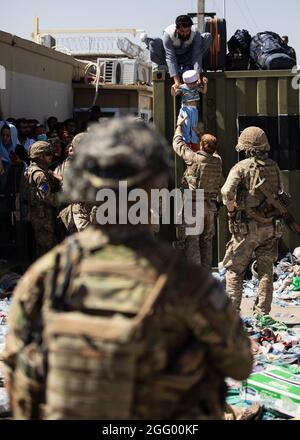 Ein afghanischer Mann übergibt sein Kind an einen britischen Fallschirmjäger, der dem 2. Bataillon des Fallschirmregiments zugewiesen ist, während die 82. Luftlandedivision als Mitglied des Kampfteams der 1. Brigade am Hamid Karzai International Airport in Kabul, Afghanistan, Sicherheitsdienste durchführt, 26. August 2021. Die 82. ABN. Div. Unterstützt weiterhin die sichere Evakuierung von US-Bürgern, Visa für Sondereinwanderer und anderen gefährdeten Afghanen aus Afghanistan so schnell und sicher wie möglich. (USA Foto der Armee) Stockfoto