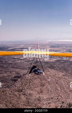 Ein Drachenflieger-Pilot startet von der Startrampe auf Horse Ridge am Dry Canyon in der Nähe von Alamogordo, New Mexico. In der Ferne ist White Sands National Stockfoto