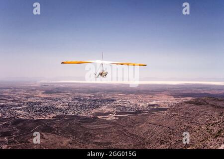 Ein Drachenflieger fliegt über das Tularosa Basin mit dem White Sands National Park im Hintergrund in der Nähe von Alamogordo, New Mexico. Stockfoto