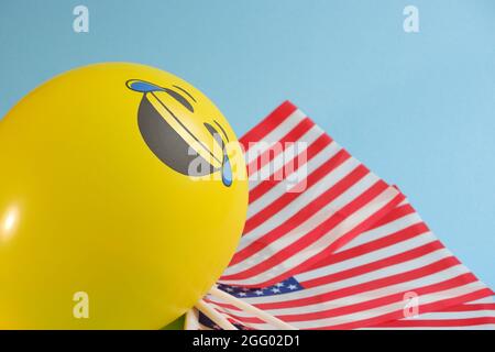 Gelbe Emoji-Ballons mit amerikanischen Flaggen auf blauem Hintergrund. Geburtstag des Emoticons. Stockfoto