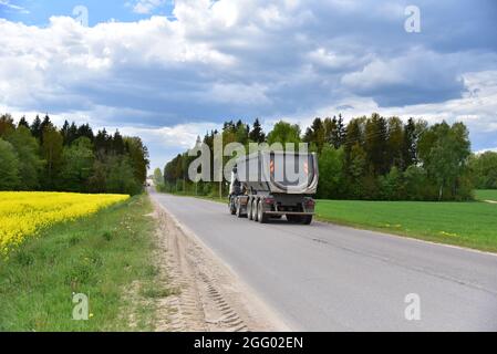 LKW mit Kipper Sattelauflieger transportierte Sand aus dem Steinbruch auf der Fahrt entlang der Autobahn. Stockfoto