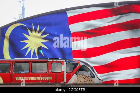 Kuala Lumpur, Malaysia. August 2021. Ein Light Rail Transit Zug fährt an einer digitalen Plakatwand mit malaysischer Nationalflagge vorbei.Malaysia feiert am 31. August jährlich den 64. Unabhängigkeitstag, auch bekannt als Nationaltag oder Hari Merdeka in Malaiisch; er erinnert an die malaiische Unabhängigkeitserklärung am 31. August 1957. (Bild: © Wong Fok Loy/SOPA Images via ZUMA Press Wire) Stockfoto