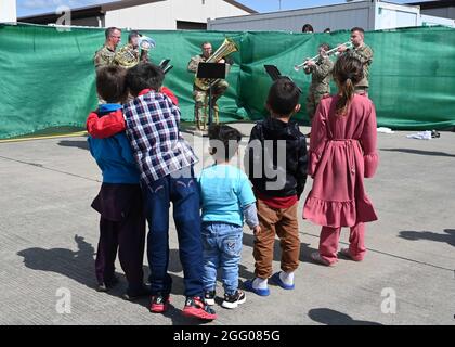 Ramstein Miesenbach, Deutschland. August 2021. Afghanische Kinder hören der U.S. Army Europe and Africa Band Musik, um Flüchtlinge auf dem Ramstein Air Base am 24. August 2021 in Ramstein-Miesenbach zu unterhalten. Der Luftwaffenstützpunkt Ramstein stellt im Rahmen der Operation Allies Refuge vorübergehend Unterkunft für Evakuierte aus Afghanistan bereit. Quelle: Planetpix/Alamy Live News Stockfoto