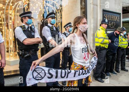 LONDON, ENGLAND- 24. August 2021: Extinction Rebellion protestiert gegen Fossil Fuel Fashion vor Selfridges in der Oxford Street Stockfoto