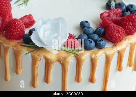 Nahaufnahme eines Kuchens - ein sehr lustloser Kuchen. Dekoration mit Himbeeren und Blaubeeren. Stockfoto