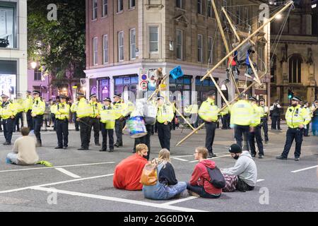 London, Großbritannien. August 2021. Extinction Rebellion (XR) und Rebellion von Tieren Protestierende besuchen den Londoner Finanzdistrikt , Quadratmeile, bis in die Nacht, besetzen die Landhauskreuzung von Queen Victoria Street und Cannon Street, bis zur Bank of England, Gegen den globalen Klimawandel. Klettern Sie auf Holzkonstruktionen, die mitten auf der Straße errichtet wurden. Um gegen Investitionen in die fossilen Brennstoffe zu protestieren. Demonstranten sitzen auf der Straße und beobachten Demonstranten, die auf Bambusstrukturen sitzen. Quelle: Xiu Bao/Alamy Live News Stockfoto