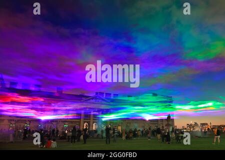 Greenwich, London, Großbritannien. August 2021. Die Menschen beobachten das Spektakel. An seiner offiziellen öffentlichen Startnacht beleuchtet „Borealis“ von Dan Archer den Himmel über dem Old Royal Naval College im Royal Borough of Greenwich. „Borealis“ ist eine faszinierende Nachbildung der Nordlichter am Himmel. Es ist Teil des jährlichen Greenwich and Docklands Festivals, das vom 27. August bis 11. September 2021 stattfindet. Kredit: Imageplotter/Alamy Live Nachrichten Stockfoto