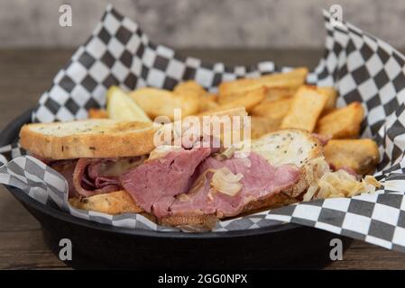 Reuben Sandwich mit Corned Beef auf gegrilltem Roggenbrot serviert mit Steak french Fries für eine appetitliche Mahlzeit. Stockfoto