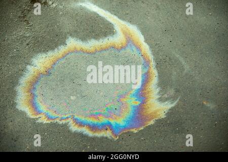 Ein Benzinfleck auf dem Asphalt. Spur von verschüttetem Kraftstoff. Alle Farben in brennbaren Flüssigkeiten. Stockfoto