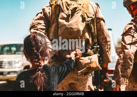 Eine Marine, die der Special Purpose Marine Air Ground Task Force – Crisis Response – Central Command zugeordnet ist, begleitet ein Kind, das während einer Evakuierung am Hamid Karzai International Airport, Kabul, Afghanistan, im August 25, verarbeitet wird. US-Dienstmitglieder und Koalitionspartner unterstützen das Außenministerium bei einer nicht-kämpferischen Evakuierungsoperation (NEO) in Afghanistan. (USA Marine Corps Foto von Sgt. Isaiah Campbell) Stockfoto