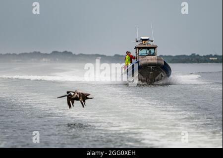 Die US-Luftstreitkräfte, die der 38. Rettungsstaffel zugewiesen wurden, reisen mit einem Boot zurück zum Ufer, nachdem sie Wassersprungtraining für die 38. RQS-Pararescuemen auf dem Banana River in der Nähe der Patrick Space Force Base, Florida, durchgeführt haben, 24. August 2021. Das Training wurde entwickelt, um Pararescuemen für die Unterstützung des SpaceX-Programms für die Raumfahrt und des Raumfahrtprogramms von Boeing vorzubereiten. Nach dem Fallenlassen von Personal oder Fracht werden die SICHEREN Boote verwendet, um Fallschirme und andere Materialien aus dem Wasser zu holen. (USA Foto der Luftwaffe von Staff Sgt. Devin Boyer) Stockfoto