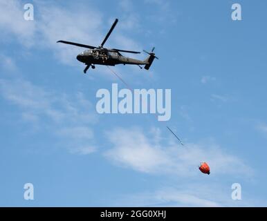 Eine US-amerikanische US-amerikanische Militärs-Militärs-Besatzung der UH-60 Black Hawk mit einem Zug des 1. Bataillons des 147. Luftfahrtregiments in Madison, Wisent, um Wasser auf Waldbrände zu werfen, der am 12. August 2021 Bambi-Eimer an einem See in Fort McCoy, Wisent, in Vorbereitung auf den Einsatz nach Kalifornien benutzte. Zwei Flugzeuge und 17 Truppen der Einheit verließen Wisconsin am 13. August 2021, um in Kalifornien Waldbrände zu bekämpfen. (USA Army Photo von Greg Mason, Fort McCoy Multimedia-Visual Information Office) Stockfoto