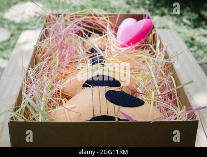 Spielzeug Plüsch Gitarre und ein rosa Herz in einer Geschenkbox mit bunten Papierstreifen gefüllt, Jahrestag Feier schöne Geschenkidee. Stockfoto