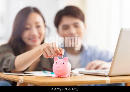 Glückliches Paar Münze in Sparschwein einfügen.Familienfinanzierung.Fokus auf Sparschwein. Stockfoto