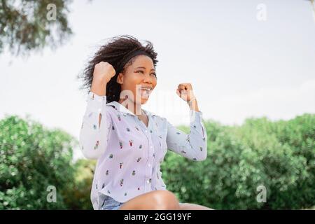 Fröhliche afroamerikanische Frau, die den Sieg in einem Park feiert. Stockfoto