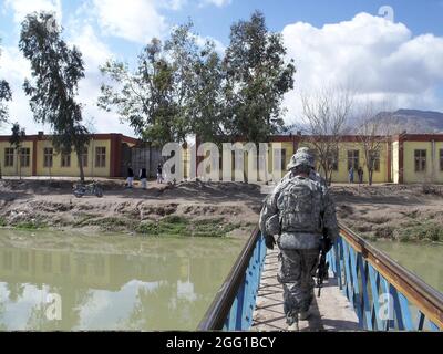 Nangarhar Provincial Reconstruction Team Mitglieder eine Fußgängerbrücke überqueren einen Kanal zur Durchführung einer Qualitätskontrolle bei Amerkhil jungen und Mädchen Schule März 5. (Foto von US Air Force Tech Sgt. Charles Burgess) Stockfoto
