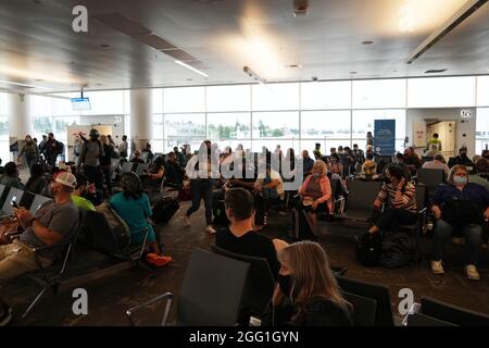 Menschen mit Gesichtsmasken sitzen im Wartebereich der N4- und N5-Spiele am Nordterminal des Seattle-Tacoma International Airport, Freitag, den Stockfoto