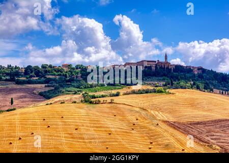 Toskanische Landschaft mit Feldern voller Getreideballen mit San Quirico de Orcia im Hintergrund. Stockfoto