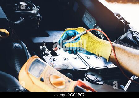 Techniker zur Überprüfung der Spannungsfestigkeit der Autobatterie mit digitaler Multimeter-Prüfspitze Stockfoto