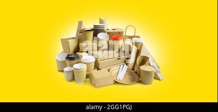 Viele verschiedene Lebensmittelbehälter zum Mitnehmen, Pizzaschachteln, Kaffeetassen im Halter und Pappschachteln auf gelbem Hintergrund. Stockfoto