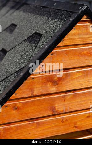 Die Fassade und das Dach des Hundezwinger. holzhaus mit Asphaltschindeln bedeckt. Nahaufnahme, selektiver Fokus. Stockfoto