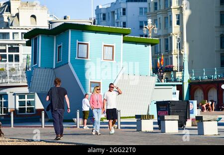 Brighton UK 28. August 2021 - am frühen Morgen passieren Wanderer das Upside Down House an der Küste von Brighton bei strahlendem Sonnenschein, da das Wetter für den Feiertag im August gut sein wird : Credit Simon Dack / Alamy Live News Stockfoto