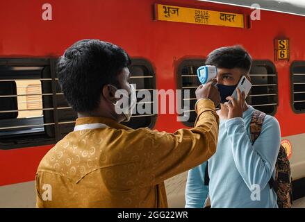 Mumbai, Indien. August 2021. Ein Mitarbeiter des Gesundheitswesens überprüft die Temperatur eines Mannes am Dadar Terminus.Passagiere, die mit dem Außenbahnhof ankommen, müssen sich einer Temperaturprüfung und in einigen Fällen einem RT-PCR-Test unterziehen, bevor sie zu ihrem jeweiligen Ziel fahren dürfen. Kredit: SOPA Images Limited/Alamy Live Nachrichten Stockfoto