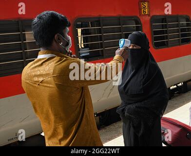 Mumbai, Indien. August 2021. Ein Mitarbeiter des Gesundheitswesens überprüft die Temperatur einer Frau am Dadar Terminus.Passagiere, die mit dem Außenbahnhof ankommen, müssen sich einer Temperaturkontrolle und in einigen Fällen einem RT-PCR-Test unterziehen, bevor sie zu ihrem jeweiligen Ziel fahren dürfen. Kredit: SOPA Images Limited/Alamy Live Nachrichten Stockfoto