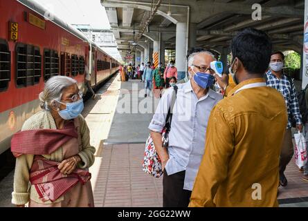 Mumbai, Indien. August 2021. Ein Mitarbeiter des Gesundheitswesens überprüft die Temperatur eines Mannes am Dadar Terminus.Passagiere, die mit dem Außenbahnhof ankommen, müssen sich einer Temperaturprüfung und in einigen Fällen einem RT-PCR-Test unterziehen, bevor sie zu ihrem jeweiligen Ziel fahren dürfen. Kredit: SOPA Images Limited/Alamy Live Nachrichten Stockfoto